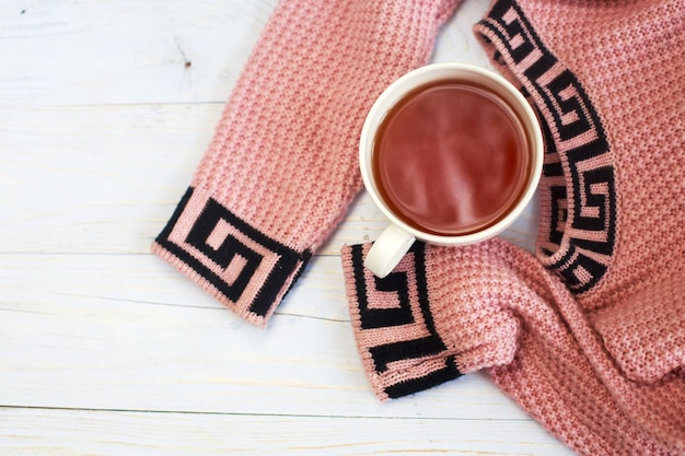 Xícara de café quente com suéter de tricô em uma mesa de madeira