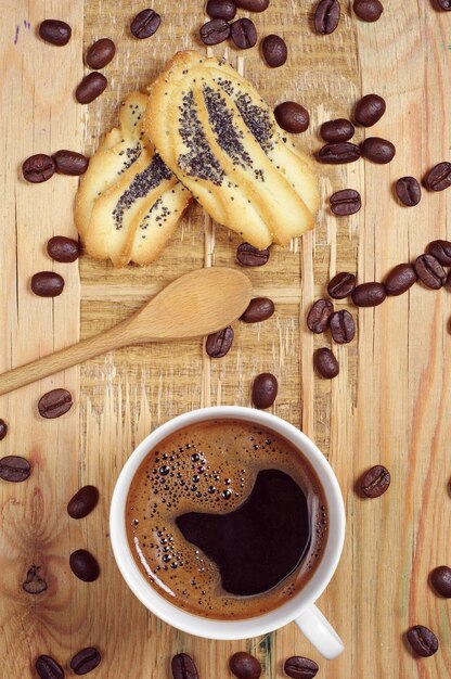 Xícara de café quente e biscoitos caseiros na velha mesa de madeira, vista superior