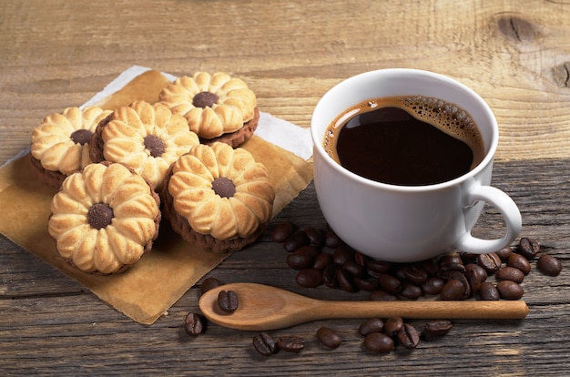 Xícara de café quente e biscoitos com chocolate no café da manhã na velha mesa de madeira