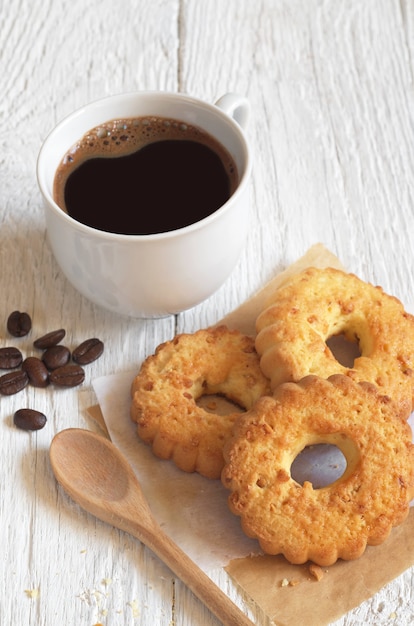 Xícara de café quente e biscoitos com nozes no café da manhã na mesa de madeira branca