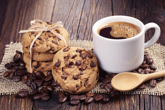 Xícara de café quente e biscoitos de chocolate amarrados com uma fita na serapilheira