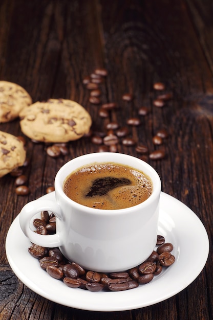 Xícara de café quente e biscoitos de chocolate na mesa de madeira vintage