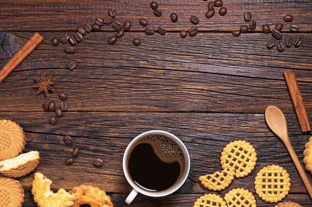 Xícara de café quente e biscoitos diferentes na vista superior da mesa de madeira escura Espaço para texto