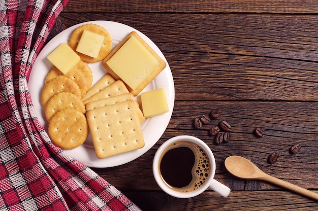 Xícara de café quente e bolachas com queijo na mesa de madeira rústica, vista superior