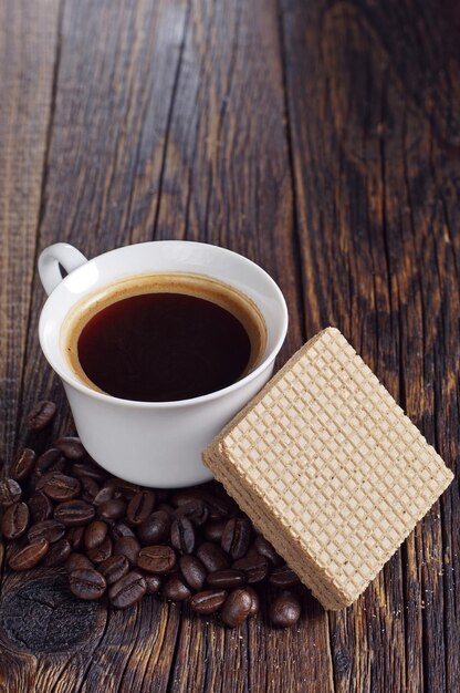 Xícara de café quente e deliciosas bolachas com chocolate na mesa de madeira escura