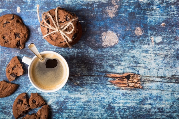 Xícara de café quente fresco, biscoitos de chocolate na velha mesa rústica de madeira azul