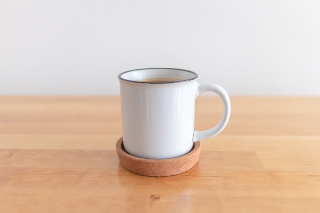 Xícara de café quente na mesa de madeira com parede branca