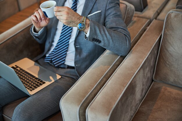 Xícara de café quente nas mãos de um empresário elegante