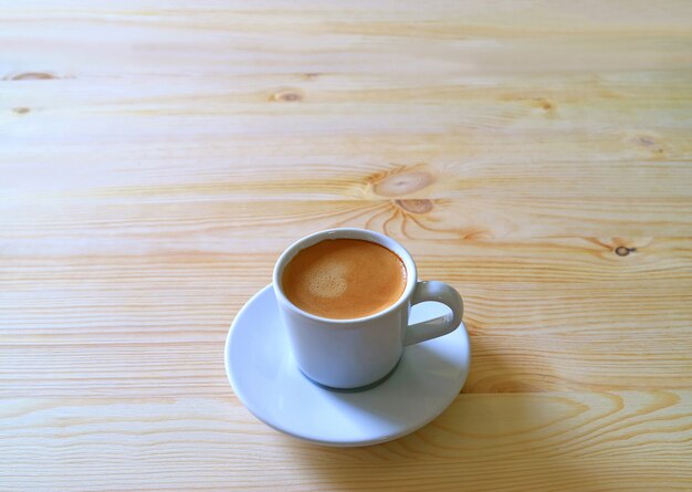 Xícara de café quente, servido em uma mesa de madeira na luz da manhã