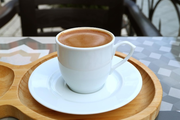 Xícara de café turco na bandeja de madeira servida na mesa ao ar livre
