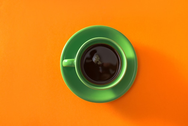 Xícara de café verde em fundo laranja