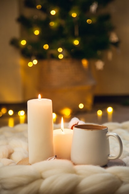 Xícara de cappuccino, biscoitos e velas no fundo do cobertor de lã grossa. A atmosfera de simplicidade e conforto.