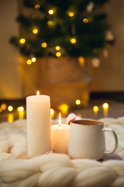 Xícara de cappuccino, biscoitos e velas no fundo do cobertor de lã grossa. a atmosfera de simplicidade e conforto.