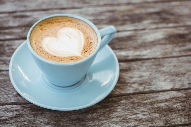 Xícara de cappuccino com arte de café na mesa de madeira na cafeteria