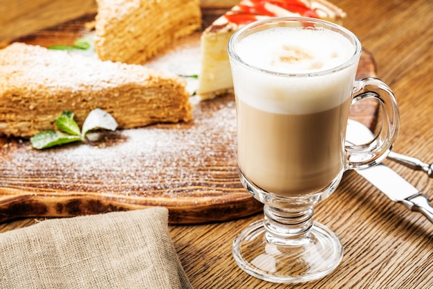 Xícara de cappuccino com café com leite em fundo de madeira copo de cerâmica verde de espuma bonita