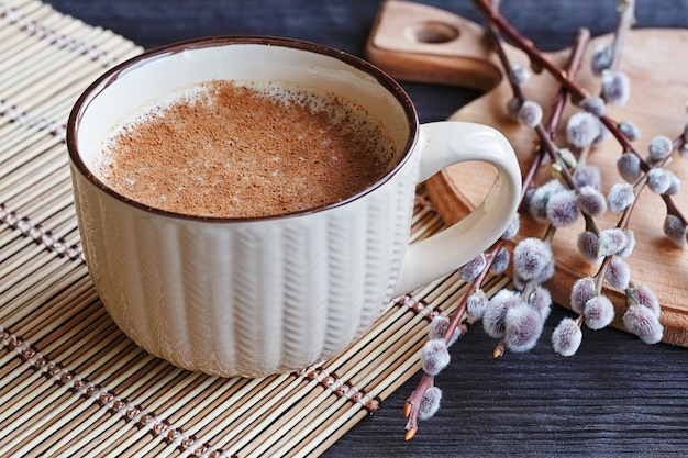 Xícara de cappuccino com canela e salgueiro na velha mesa de madeira