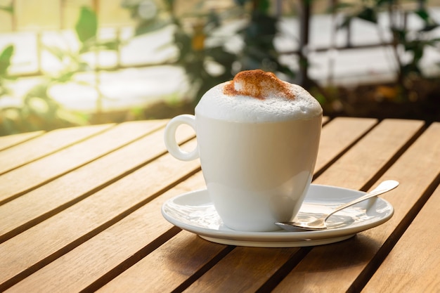 Xícara de cappuccino com canela em uma mesa de madeira em um café de rua