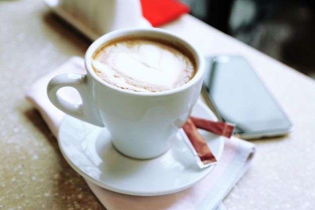 Xícara de cappuccino com coração na espuma na mesa no café