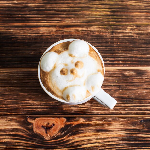 Xícara de cappuccino com latte art - focinho de urso de volume 3D na mesa de madeira