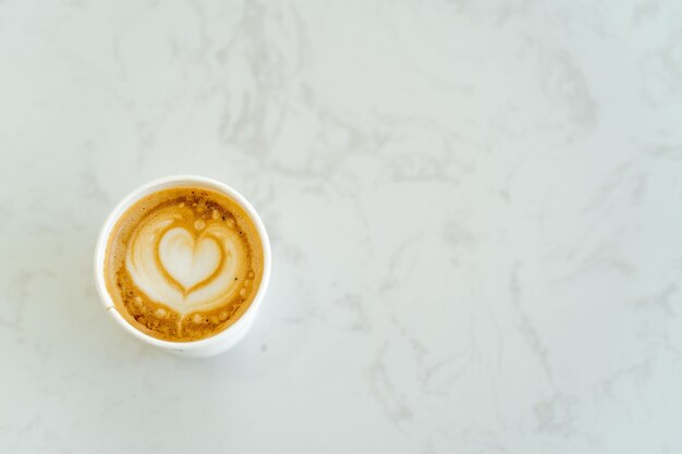 Xícara de cappuccino com padrão em forma de coração na mesa de mármore