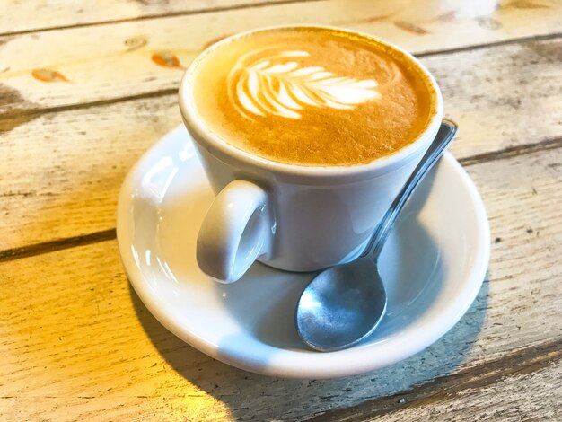 Xícara de cappuccino com padrão na mesa de madeira velha.
