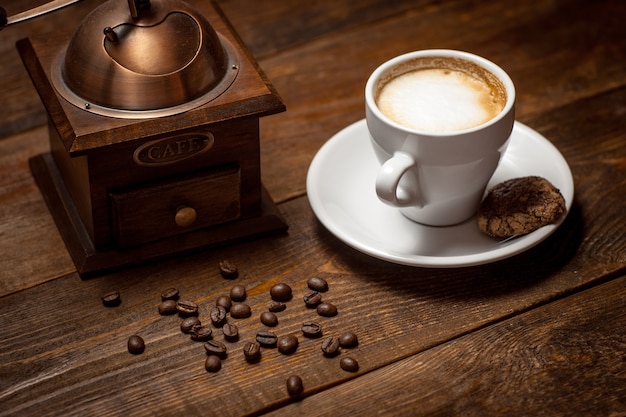 Xícara de cappuccino moedor de grãos de café na mesa de madeira