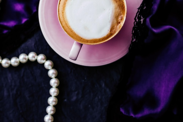 Xícara de cappuccino no café da manhã com fundo de joias de cetim e pérolas café orgânico com leite sem lactose no café parisiense para marca de férias vintage de luxo