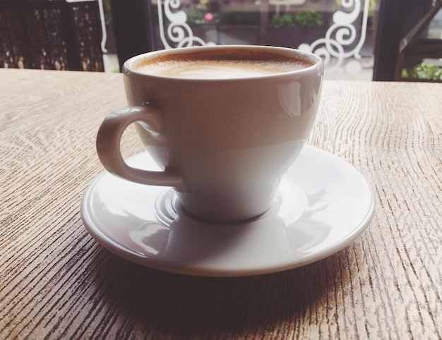 Xícara de cappuccino quente em um café de cafeteria em uma mesa de madeira no café