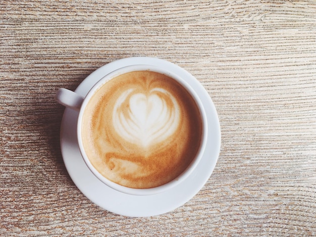 Xícara de cappuccino quente em um café de cafeteria em uma mesa de madeira no café