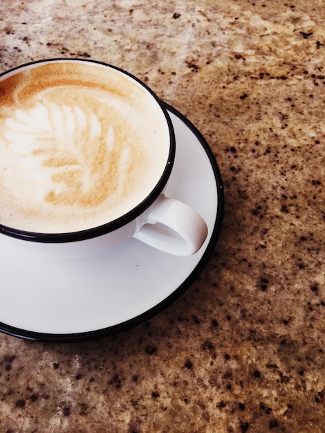 Xícara de cappuccino quente em um café de cafeteria em uma mesa de madeira