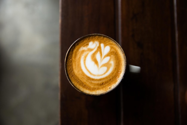 Xícara de cappuccino quente na mesa de madeira no fundo da mesa escura