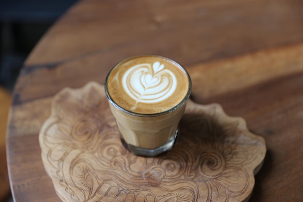 Xícara de cappuccino saboroso com latte art e colher de ouro no fundo da mesa de madeira