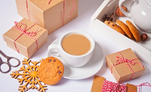 Xícara de chá, biscoito caseiro, caixas de presente de Natal e decoração de Natal em branco.