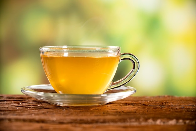 Xícara de chá com a mesa de madeira e o plano de fundo das plantações de chá.