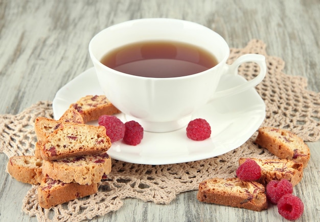 Xícara de chá com biscoitos e framboesas na mesa closeup