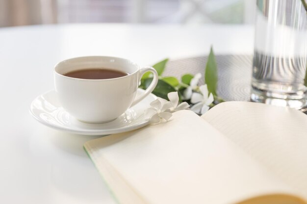 Xícara de chá com bloco de notas e flores brancas o início do dia de trabalho emoções agradáveis feliz planejamento do dia