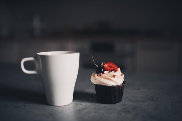 Xícara de chá com bolinho cremoso com frutas vermelhas