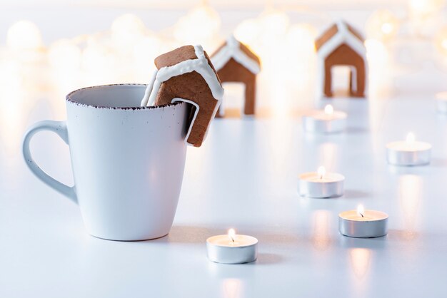 Xícara de chá com casa de pão de mel ao lado de velas. Espírito de natal. Aconchego.