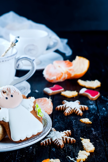 Foto xícara de chá com chá e biscoitos anjo, tangerineon uma mesa preta
