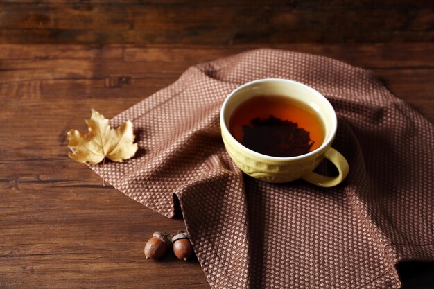 Xícara de chá com decoração de outono na mesa de madeira