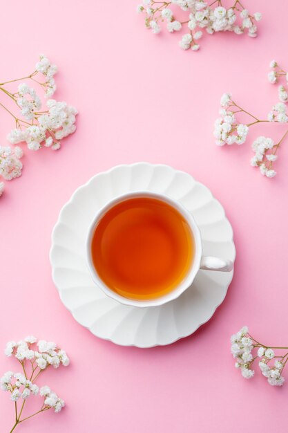 Xícara de chá com flores frescas no fundo rosa Vista superior Copiar espaço