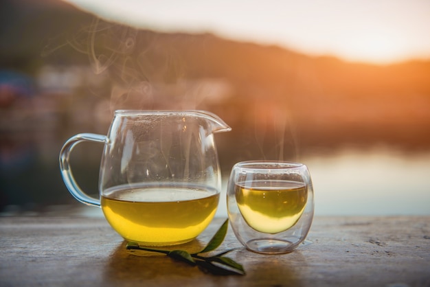 Xícara de chá com folhas de chá verde na mesa de madeira.