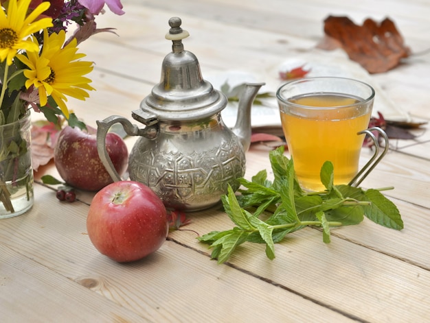 Xícara de chá com folhas de hortelã fresca em uma mesa de madeira