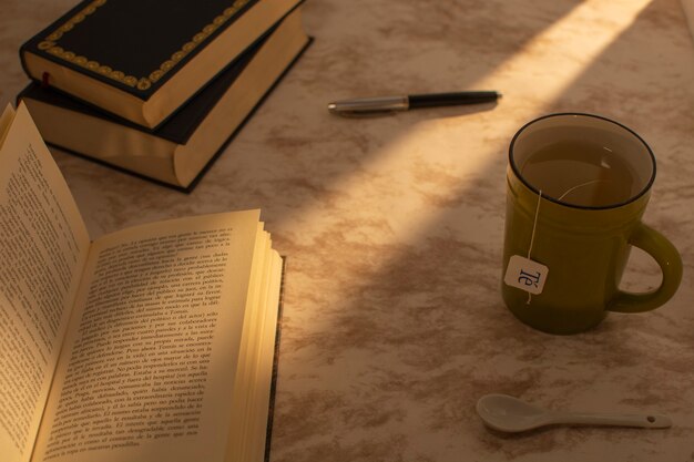 Xícara de chá com livros ao lado e uma caneta-tinteiro