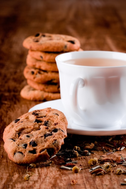 Xícara de chá de ervas e alguns biscoitos frescos closeup na mesa de madeira