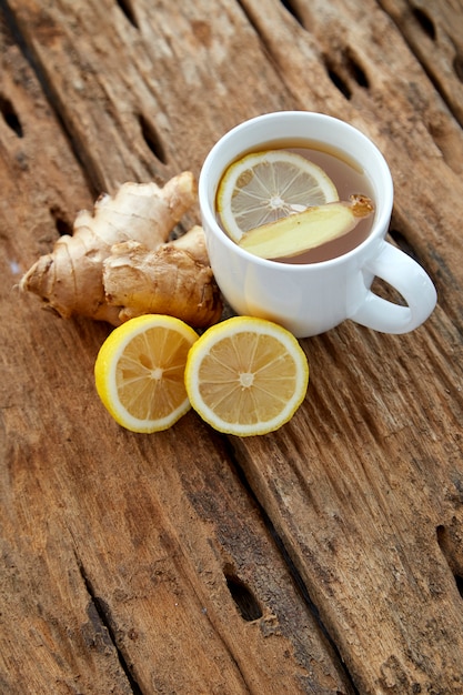 Xícara de chá de gengibre com limão em madeira
