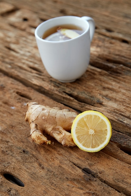 Xícara de chá de gengibre com limão em madeira