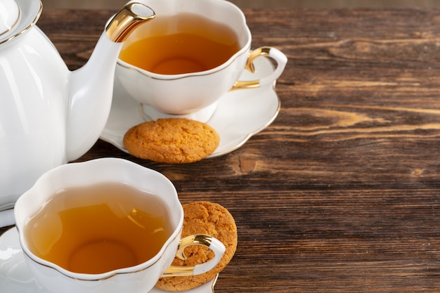 Xícara de chá de porcelana branca e biscoitos de aveia em uma mesa