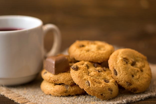 Xícara de chá e biscoitos em fundo escuro de madeira branca