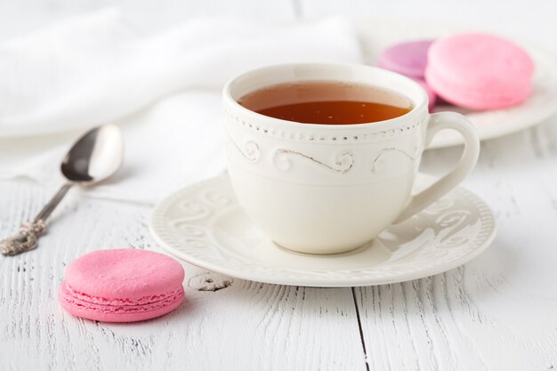 Xícara de chá e Macaroons na mesa pastel vintage